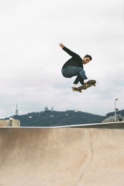 滑板者在白色天空的背景下用蛇板在空中跳得很高。垂直的图像。图片下载