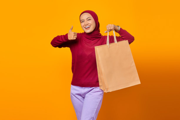 漂亮的亚洲女人拿着购物袋，微笑着竖起大拇指图片下载