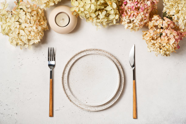 感恩节餐桌上有干花、盘子、餐具和白色背景上的蜡烛图片下载