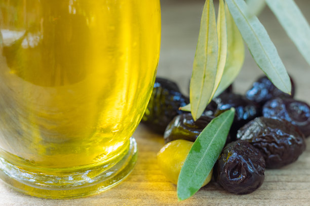 一张黑色和绿色橄榄的特写照片，旁边是一个橄榄瓶子和一片橄榄树叶图片下载