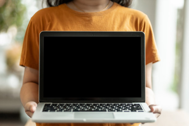 特写的自由职业人士的商业女性随意举起并展示笔记本电脑与一个空白的白色屏幕在咖啡馆的背景，沟通的概念图片下载