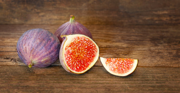 木制背景上放着无花果和一片切好的无花果图片下载