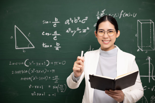 年轻的亚洲女教师手持书本和粉笔教学视频会议与学生看着摄像机。女教师从网络课程培训数学课堂黑板。图片下载