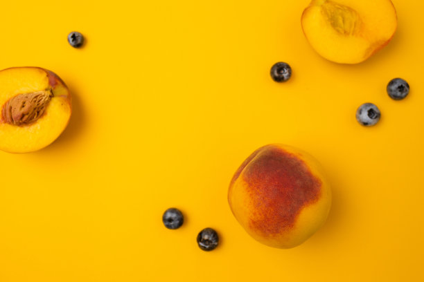 平坦的构图与成熟的桃子在彩色背景。由新鲜的桃子制成的框架。图片下载