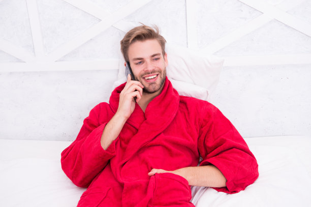 现代生活离不开手机通讯。现代男人在床上用智能手机聊天。帅哥在家里用现代手机打电话。现代科技用于日常生活图片下载