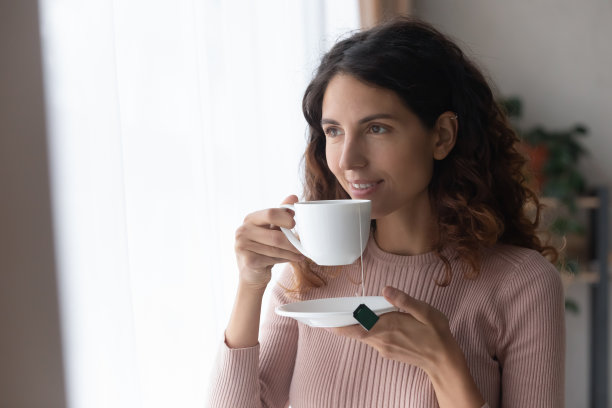 在室内端着茶杯站立的微笑女人图片下载