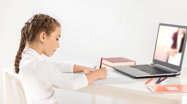 一名女学生坐在桌子前的笔记本电脑前学习图片下载