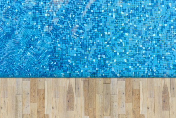 游泳池和木板的俯视图。蓝色马赛克瓷砖游泳池底部的水波纹。图片下载