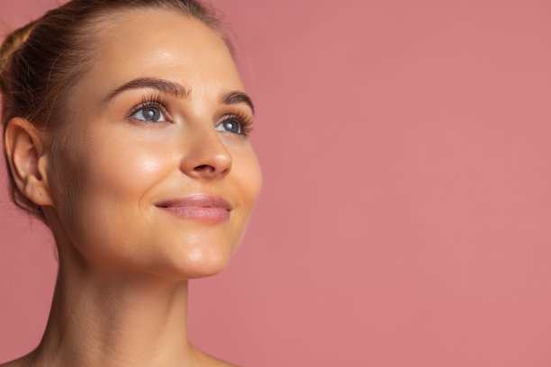 短发特写年轻美丽的女孩与发髻孤立在粉红色的背景图片下载