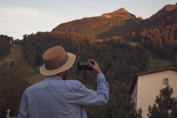 一名男子用手机拍下了山的照片图片下载