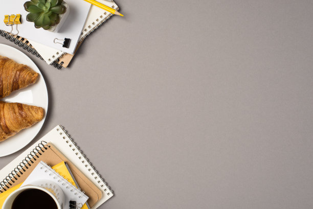 顶视图照片的工作场所文具堆栈计划装订夹夹铅笔植物杯饮料和新鲜的羊角面包在孤立的灰色背景与copyspace图片下载
