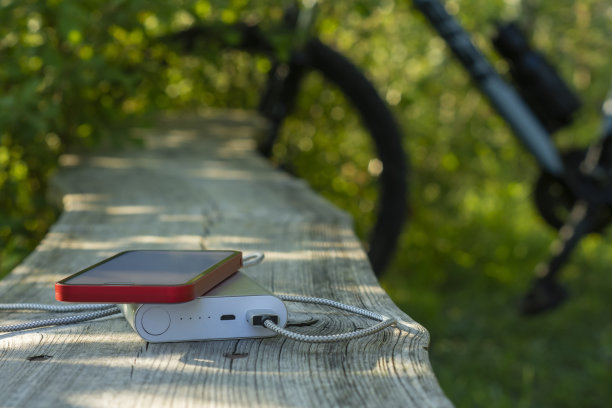 移动银行在森林里以自行车为背景给智能手机充电。图片下载