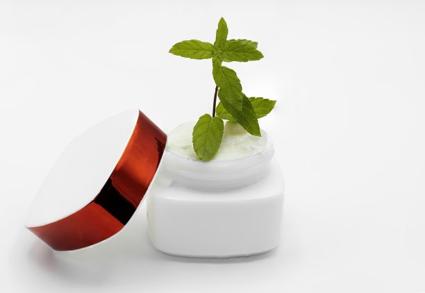 一瓶带着绿色嫩芽的保湿霜。青春美概念图片下载