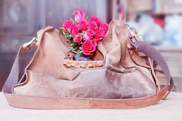 旧棕色绒面革袋和玫瑰花束图片下载