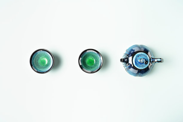 深蓝色陶土茶壶和蓝色背景的小杯子中的绿茶。平的风格。创造性的极简主义的布局。图片下载