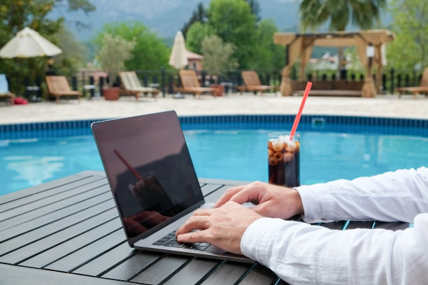 泳池边拿着笔记本电脑的男人图片下载