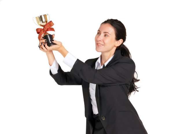 一位身穿黑色西装的女商人面带微笑，自豪地看着从工作中获得的奖杯。人像在白色背景与工作室灯光。图片下载