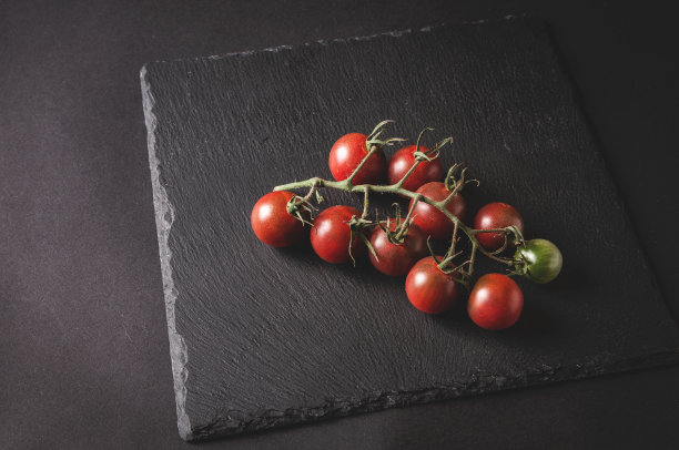 一串新鲜的樱桃番茄放在一个黑色的服务板上图片下载