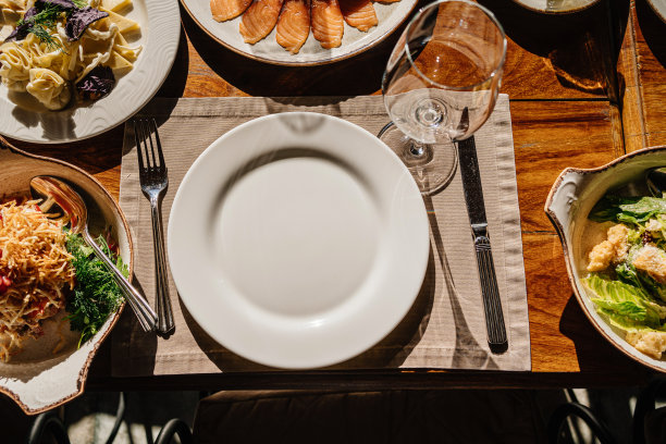 木桌上有盘子、沙拉和小吃、刀叉和玻璃杯。图片下载