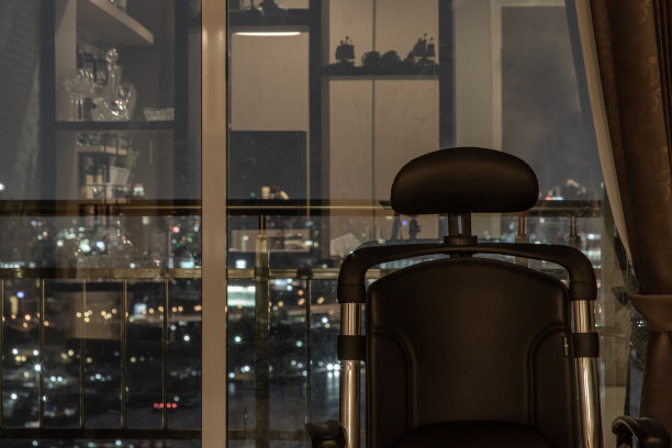 舒适的椅子在客厅和城市景观在家里，公寓在晚上。图片下载