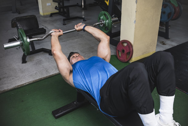 一名亚洲运动员在做一组三头肌伸展动作，也被称为粉碎头骨。在健身房锻炼肱三头肌和手臂。图片下载
