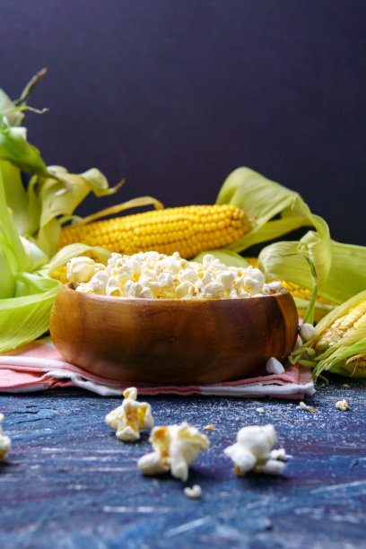 新鲜的玉米和爆米花在黑色的背景上。垂直的照片。Copyspace图片下载