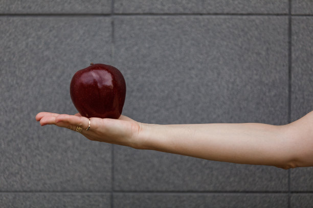 女人手里拿着一个漂亮的红苹果图片下载