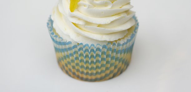 柠檬芝士奶油糖霜纸杯蛋糕，蓝色和黄色的衬纸，白色的背景横幅图片下载