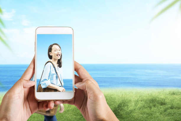 人类的手用手机拍下了亚洲女人带着行李箱在球场上旅行的照片图片下载