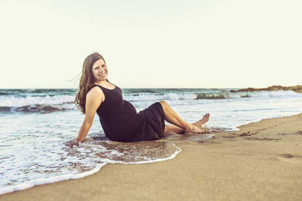 微笑的孕妇在海滩上放松，对着镜头微笑图片下载