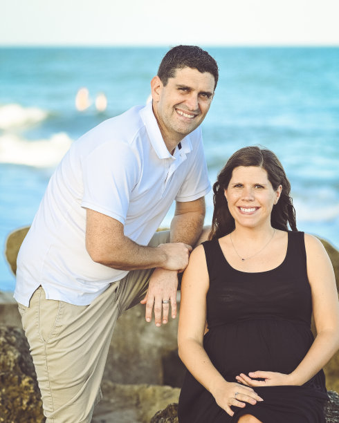 一对英俊的异性恋夫妇和一个怀孕的女人在大海前摆姿势拍照图片下载
