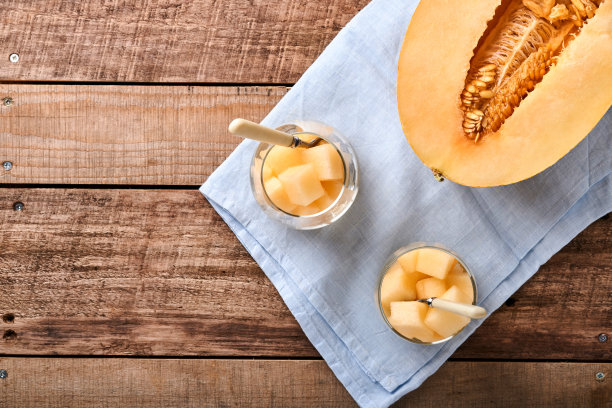 瓜。在一个古老的木制背景上，用玻璃制作水果甜点的新鲜甜瓜片。模拟。前视图。图片下载