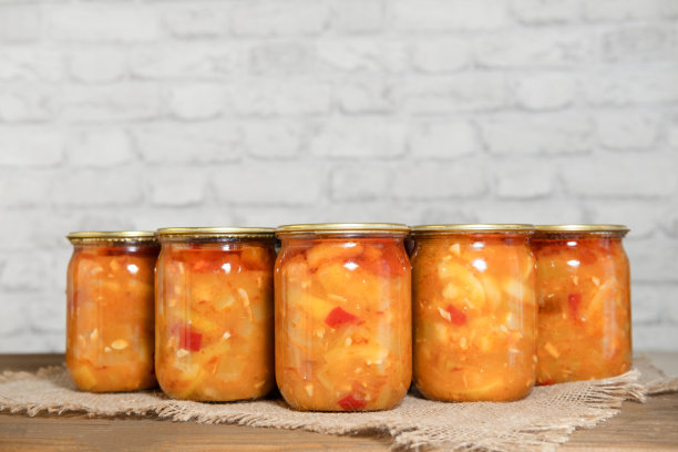 木桌上放着装在玻璃罐里的西葫芦片和蔬菜罐头。准备过冬。西葫芦开胃菜。图片下载