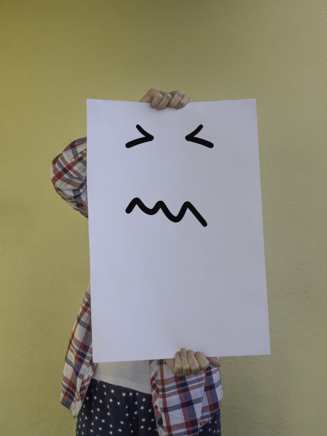 一个随意的女人把她的脸藏在一个空白的广告牌后面，一脸的愤怒图片下载