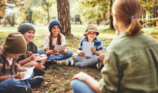 微笑的孩子和女老师围坐在草地上图片下载