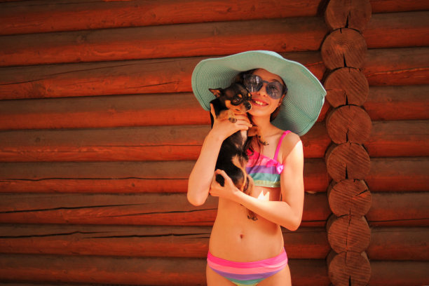 美丽的年轻女孩抱着宠物狗吉娃娃在户外。夏天的肖像。团聚。图片下载