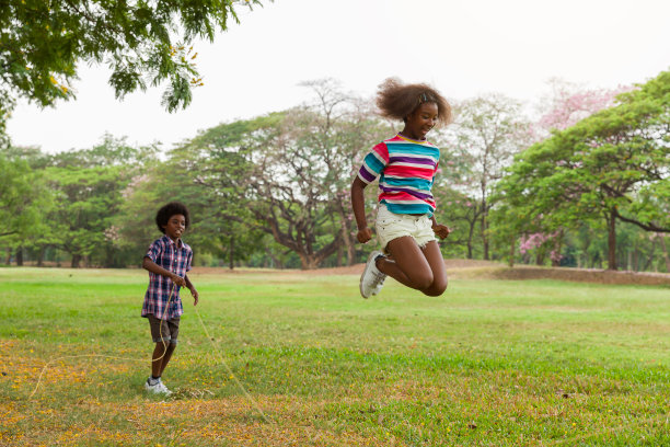 一群非洲裔美国孩子在公园里玩跳绳。欢快的孩子在室外跳绳。快乐的黑人一起在绿色的草地上玩耍图片下载