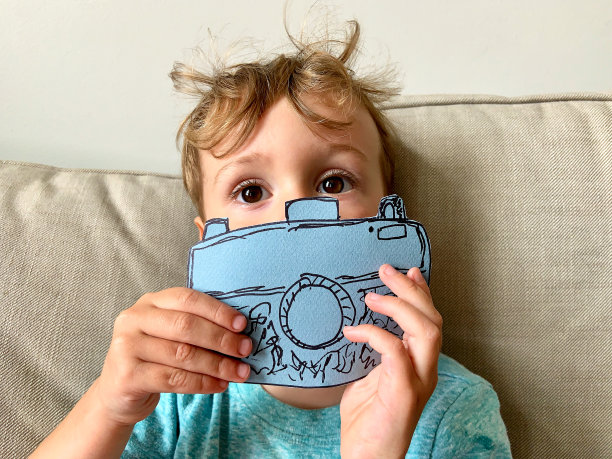 蹒跚学步的男孩拿着纸相机图片下载