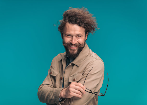开心的男模特，留着小胡子，拿着眼镜，面带微笑图片下载