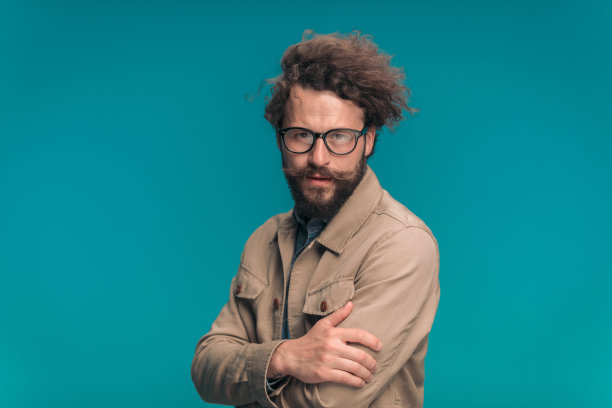 性感的年轻男子长胡子和小胡子折叠手臂图片下载