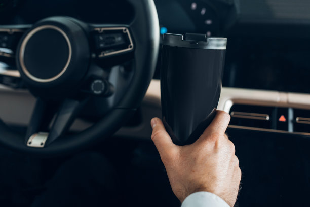 一个男人拿着热水杯开着一辆昂贵的车图片下载