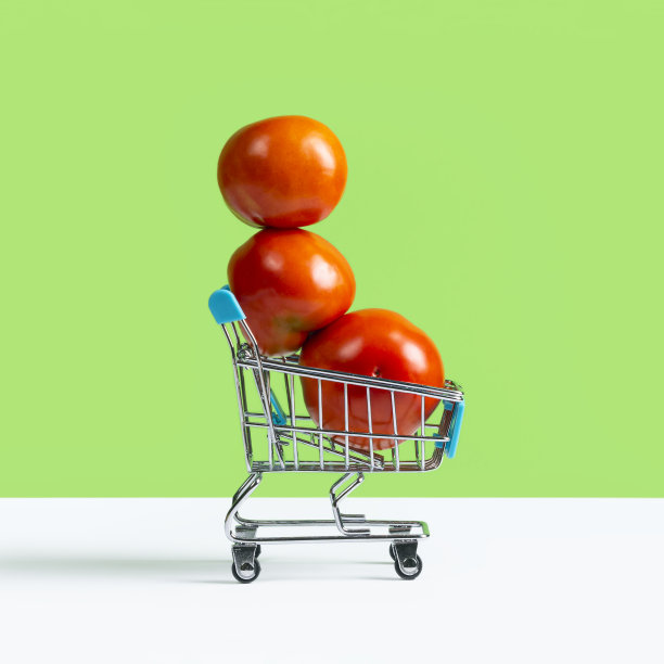 玩具购物车或手推车装满了大的红色西红柿孤立在绿色背景。秋收销售理念图片下载