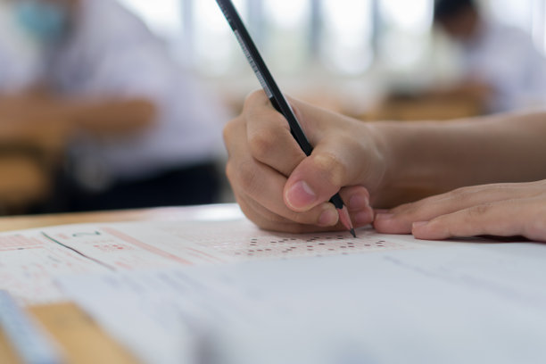 亚洲学生手握铅笔做多项选择题测验或测验答题卡在木桌上练习在中学，大学，大学的课堂教育概念图片下载