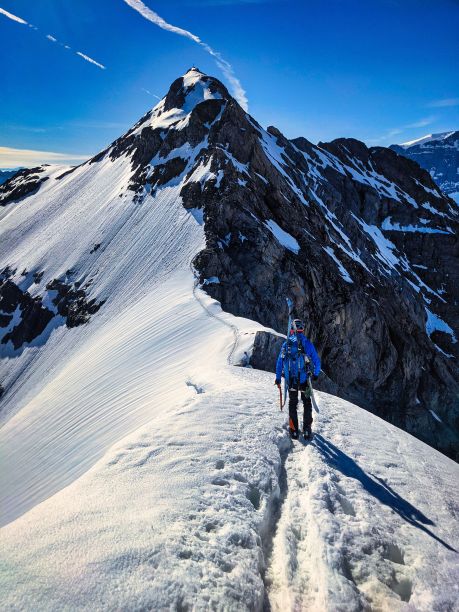 滑雪登山运动员在雪冰山脊上欣赏克拉瑞登山的景色。背上滑雪，美丽的山景图片下载