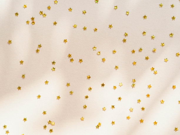 金色的星星以五彩纸屑的形式出现在米色的背景上图片下载