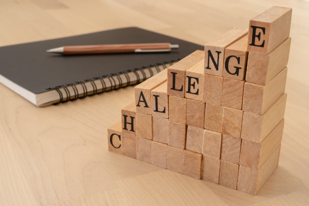 挑战;带有“挑战”概念文本的木制邮票，一个笔记本和一支笔。图片下载