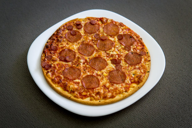 白色方形盘子上的圆形意大利腊肠披萨图片下载