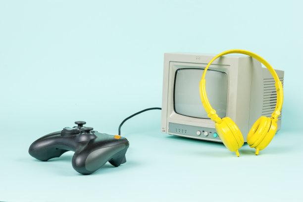 一个灰色的显示器，一个游戏机和黄色的耳机在浅蓝色的背景下。图片下载