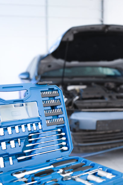 汽车工具在一个蓝色的近距离盒子里，为维修和保养车辆提供服务。背景中有一辆引擎盖抬高的汽车离焦。图片下载