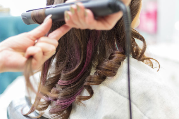 美容院的一位师傅给一个长发女孩卷了卷发。图片下载